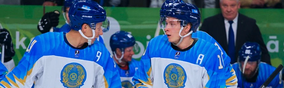 Игроки хоккейной сборной в голубой форме обсуждают игру на скамейке — 1xbet