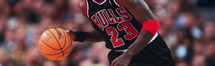 Баскетболист в форме Bulls делает рывок с мячом во время матча, спортивный динамичный момент, 1XBET